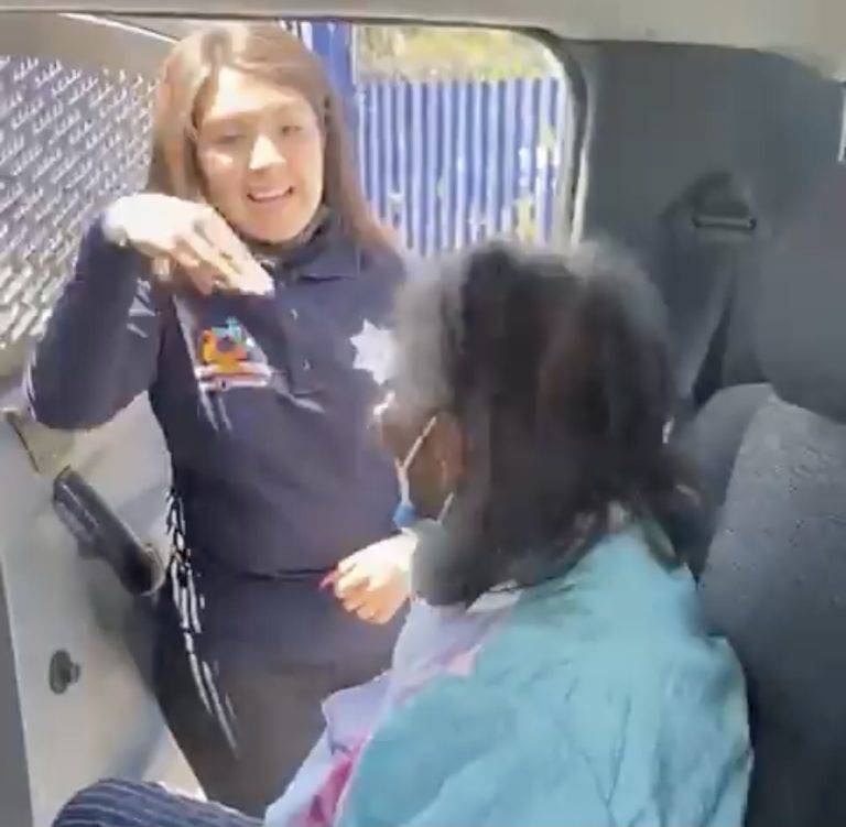 Mujer policía explica con lenguaje de señas a una abuelita cómo la vacunarán